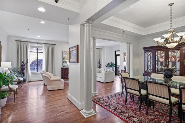 dining area with a notable chandelier, ornamental molding, wood finished floors, and ornate columns