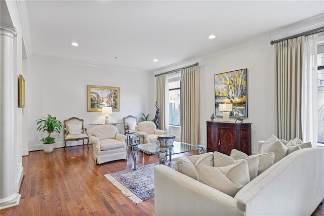 living room featuring ornamental molding, recessed lighting, wood finished floors, and ornate columns