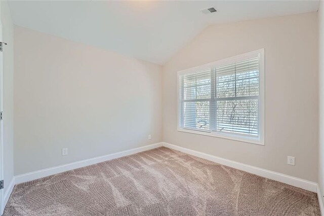 spare room with carpet and vaulted ceiling