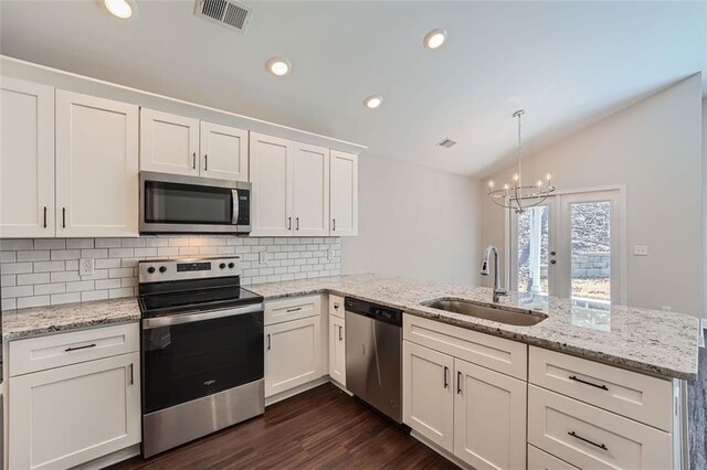 kitchen with lofted ceiling, white cabinets, sink, appliances with stainless steel finishes, and kitchen peninsula