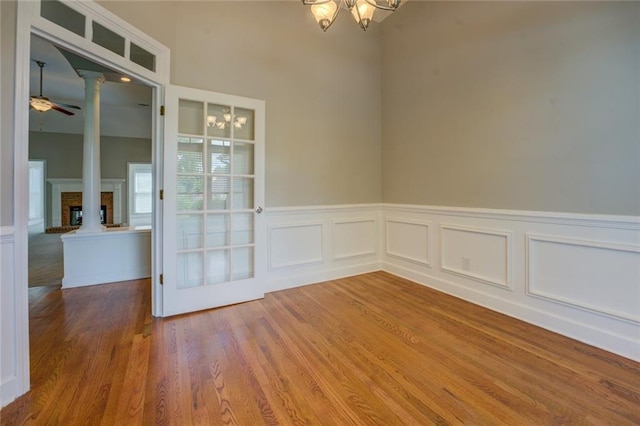 1065 Chippewa Oak Dr, Dacula, GA 30019 - empty room with a chandelier, ornate columns, wainscoting, wood finished floors, and a brick fireplace