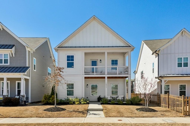 view of front of house featuring a balcony, fence, a standing seam roof, board and batten siding, and metal roof