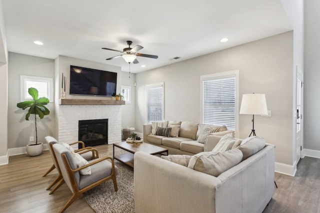 living room with visible vents, baseboards, wood finished floors, and a fireplace