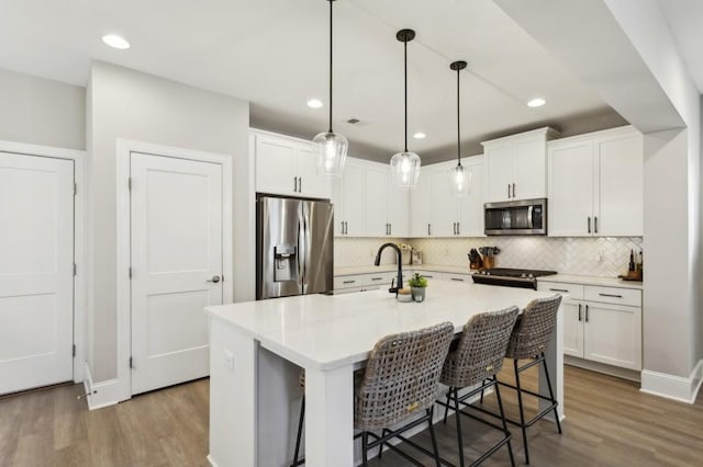 kitchen featuring stainless steel appliances, wood finished floors, and white cabinets