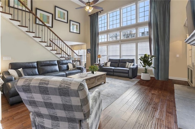 living room with hardwood / wood-style flooring, a high ceiling, and ceiling fan