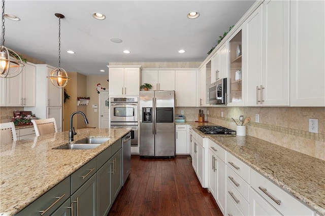 kitchen with stainless steel appliances, white cabinetry, decorative light fixtures, and sink