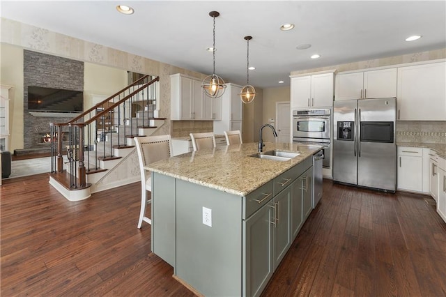 kitchen with appliances with stainless steel finishes, an island with sink, and white cabinetry