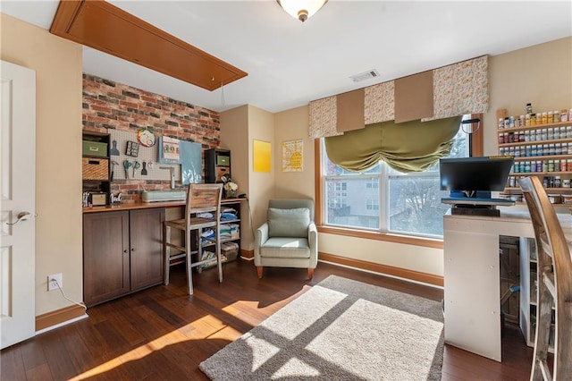 office area featuring dark wood-type flooring and brick wall