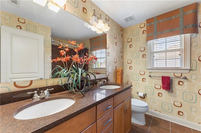 bathroom featuring toilet, a healthy amount of sunlight, tile patterned flooring, and vanity