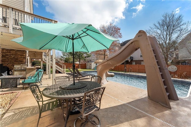 view of patio / terrace featuring exterior kitchen, a fenced in pool, area for grilling, and a storage unit