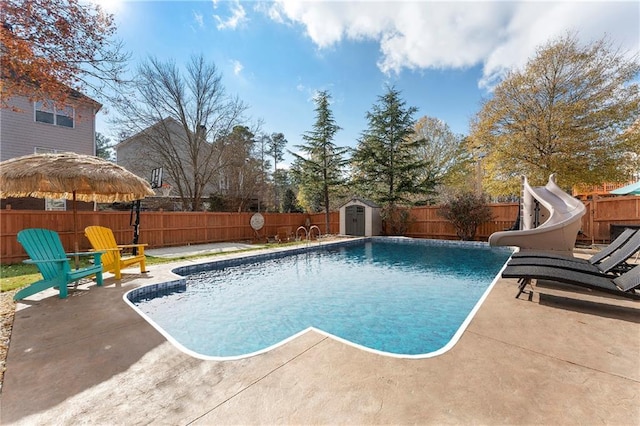 view of pool featuring a patio area, a storage shed, and a water slide