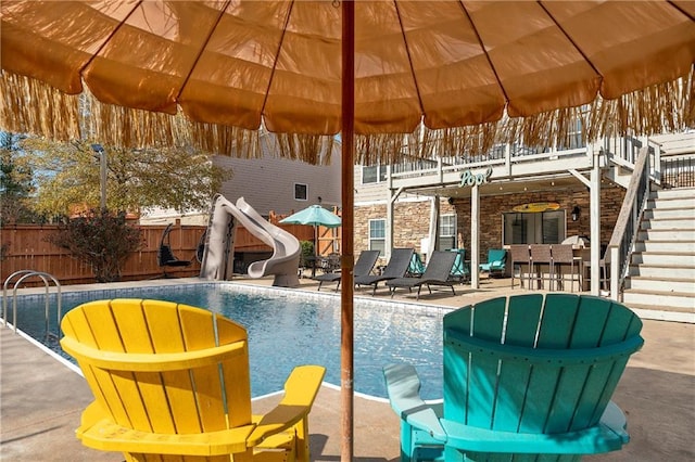 snow covered pool with exterior bar, a patio area, and a water slide