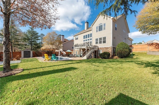 rear view of house with a storage shed, a yard, a patio, and a wooden deck