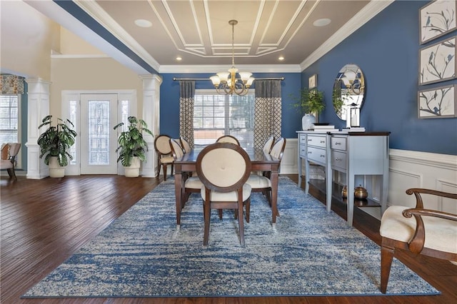 dining space featuring dark wood-type flooring, ornate columns, ornamental molding, and an inviting chandelier