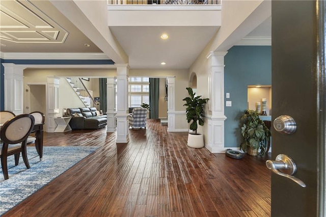 foyer featuring crown molding, dark hardwood / wood-style flooring, and ornate columns