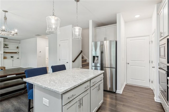 6360 Boulder Rdg, Cumming, GA 30028 - kitchen with appliances with stainless steel finishes, dark wood finished floors, hanging light fixtures, a kitchen island, and open floor plan