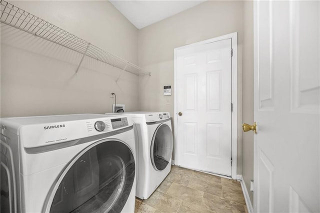 clothes washing area with washer and clothes dryer, laundry area, and stone finish floor