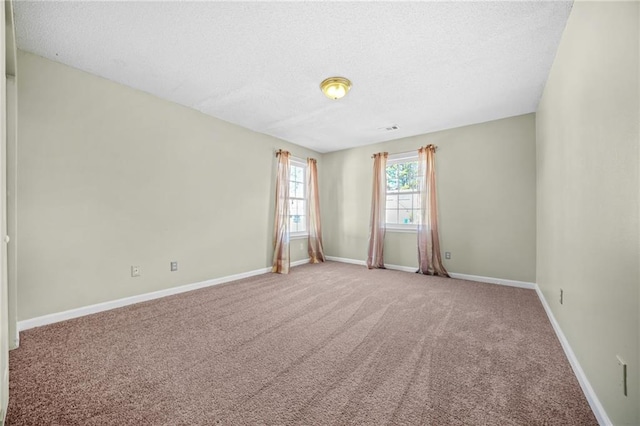 carpeted spare room with baseboards and a textured ceiling