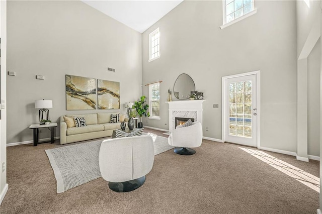 carpeted living area featuring baseboards, a high end fireplace, and visible vents