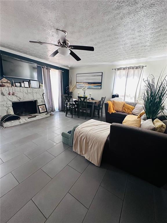 4312 Idlewood Ln, Tucker, GA 30084 - tiled living area with a ceiling fan, a textured ceiling, crown molding, and a stone fireplace