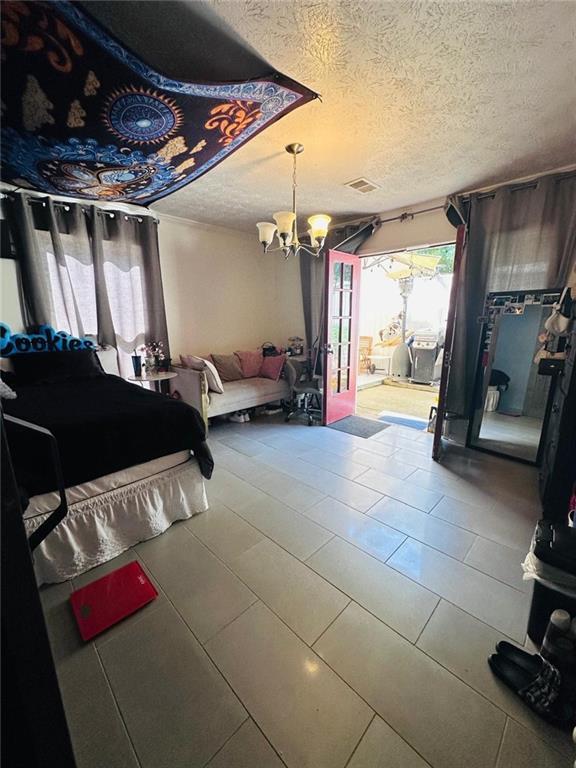 4312 Idlewood Ln, Tucker, GA 30084 - bedroom featuring a chandelier, access to exterior, and a textured ceiling