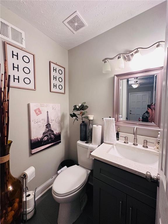 4312 Idlewood Ln, Tucker, GA 30084 - half bathroom featuring toilet, a textured ceiling, vanity, and baseboards
