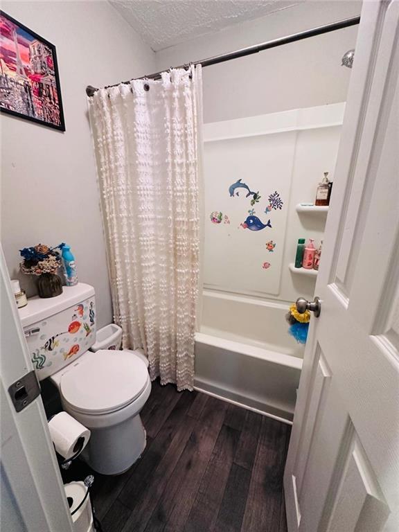 4312 Idlewood Ln, Tucker, GA 30084 - bathroom featuring toilet, wood finished floors, shower / tub combo with curtain, and a textured ceiling