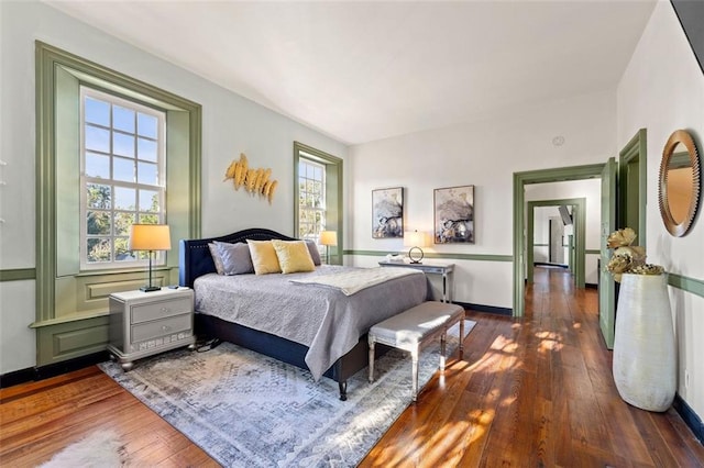 bedroom with multiple windows and dark hardwood / wood-style flooring