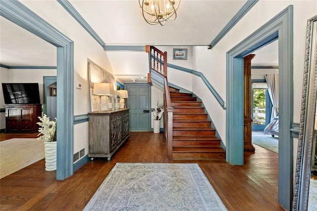 foyer entrance with a chandelier, dark hardwood / wood-style floors, and crown molding