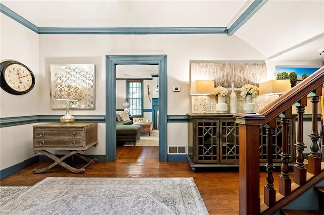 entrance foyer with dark hardwood / wood-style flooring, crown molding, and a chandelier