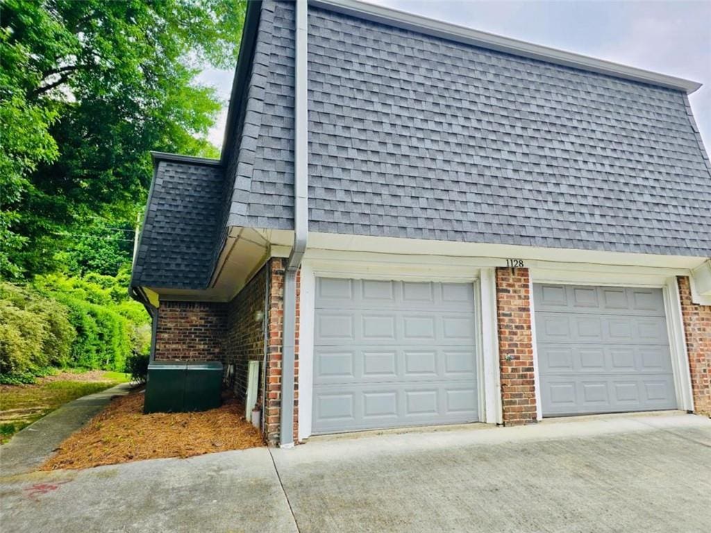 1128 Hampton Way, Atlanta, GA 30324 - view of property exterior featuring brick siding, roof with shingles, concrete driveway, and mansard roof