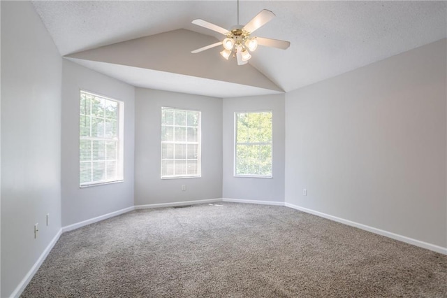 spare room featuring carpet flooring, ceiling fan, lofted ceiling, baseboards, and a textured ceiling