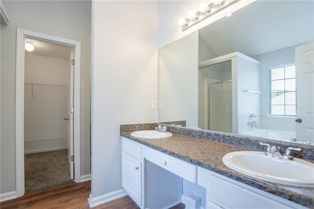 full bathroom featuring a stall shower, a spacious closet, wood finished floors, a bath, and double vanity
