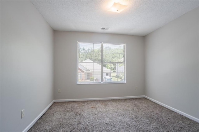 spare room featuring a textured ceiling, carpet floors, and baseboards