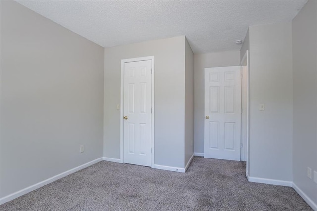 unfurnished bedroom featuring carpet floors, baseboards, and a textured ceiling