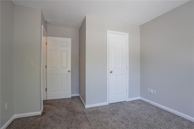unfurnished bedroom with carpet floors, baseboards, and a textured ceiling