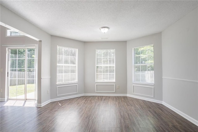 unfurnished dining area featuring dark wood finished floors, a textured ceiling, and baseboards