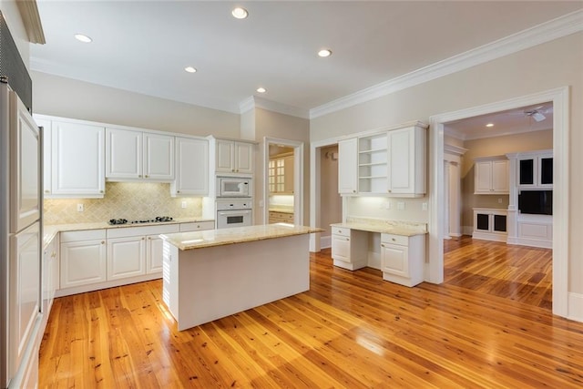 kitchen with light hardwood / wood-style flooring, a center island, white appliances, and white cabinetry