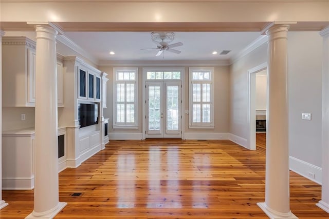 unfurnished living room with ornate columns, light wood-type flooring, crown molding, and ceiling fan