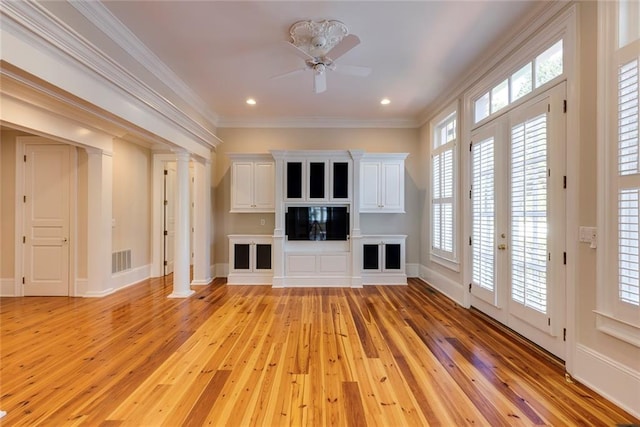 unfurnished living room with crown molding, decorative columns, light wood-type flooring, and ceiling fan