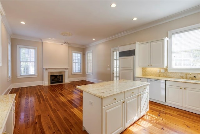 kitchen with a healthy amount of sunlight, light hardwood / wood-style flooring, a center island, and white dishwasher