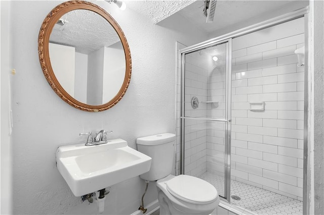 bathroom featuring a textured wall, a sink, a shower stall, and toilet