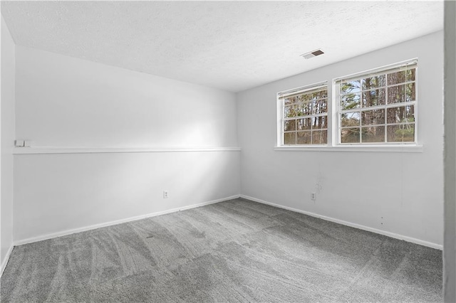 carpeted spare room featuring a textured ceiling, visible vents, and baseboards