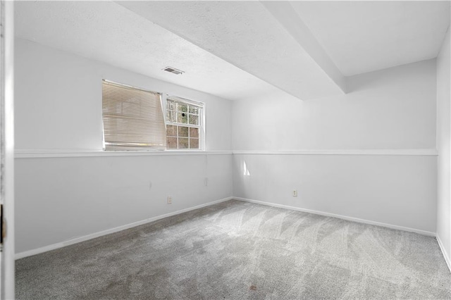 carpeted spare room with visible vents, baseboards, and a textured ceiling