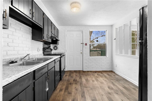 kitchen with electric stove, light countertops, freestanding refrigerator, a sink, and a textured ceiling