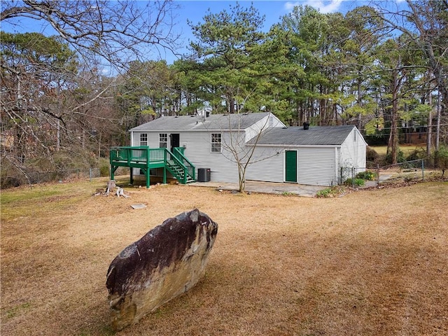 rear view of property featuring a yard, fence, a wooden deck, and central air condition unit