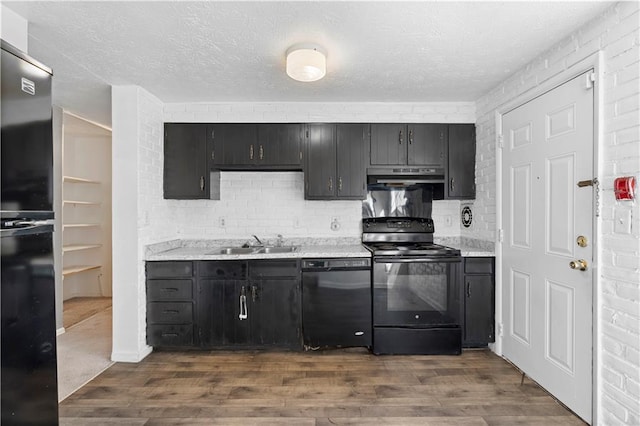 kitchen with black appliances, under cabinet range hood, dark wood finished floors, and a sink