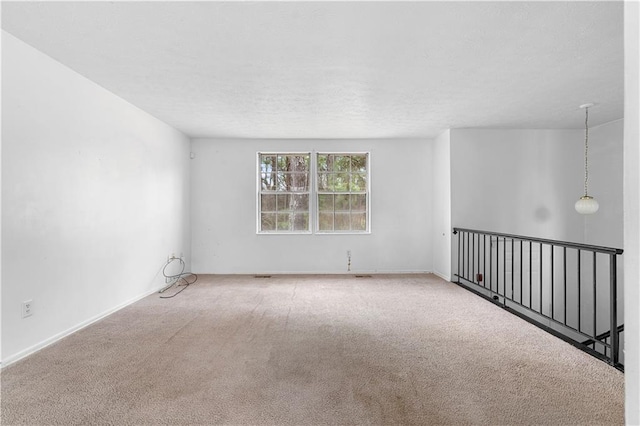 unfurnished room with a textured ceiling, carpet floors, and baseboards