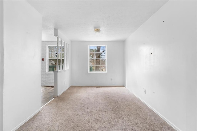 spare room featuring carpet, a textured ceiling, and baseboards