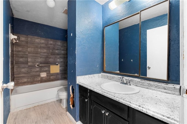 bathroom featuring toilet, wood finished floors,  shower combination, a textured ceiling, and vanity